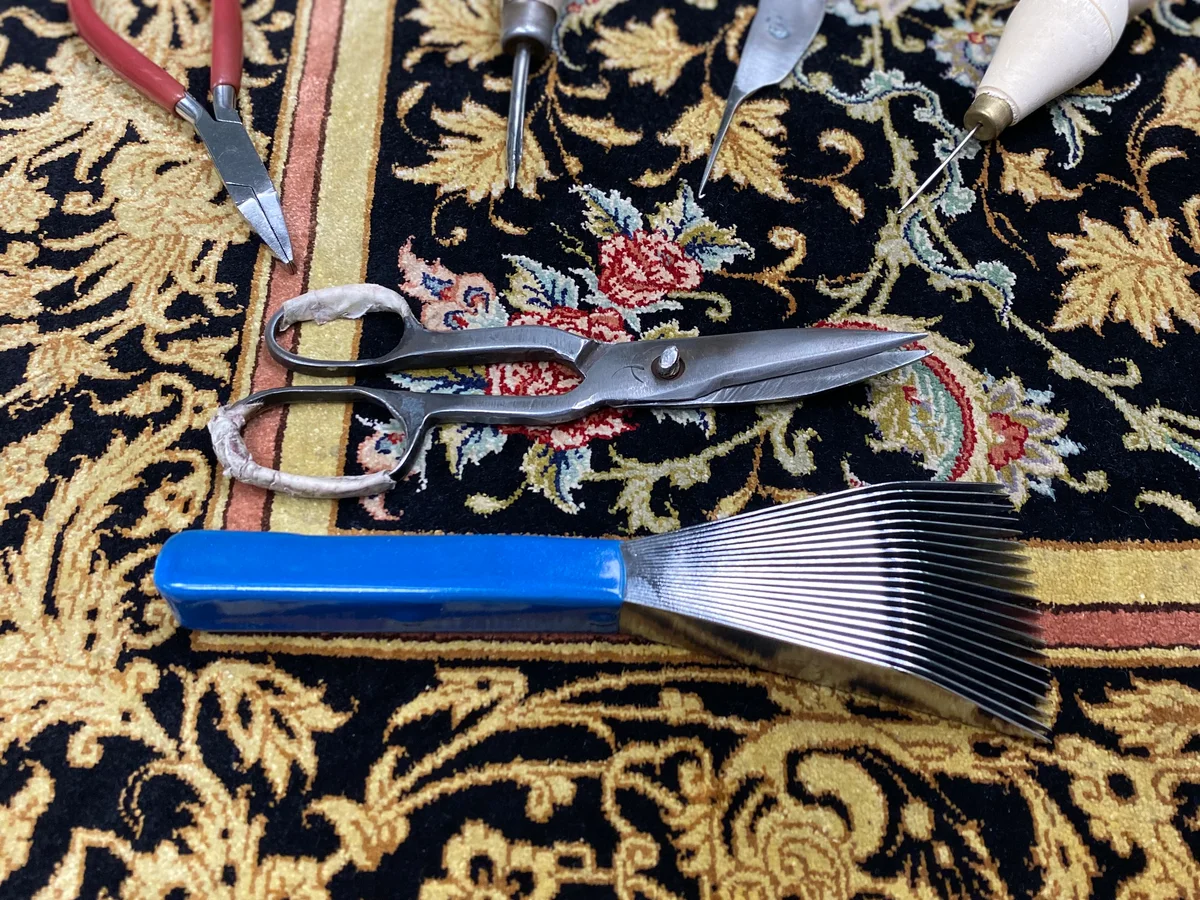 Outils de travail et ciseaux posés sur un tapis à motifs, photographie de l’Atelier Prestige